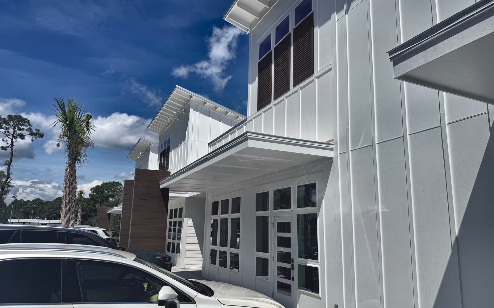 The white two-story building at 3220 Amelia Road, with the Suite 3 entrance under the covered walkway.